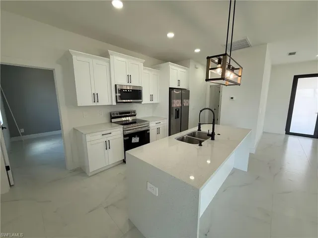 Kitchen featuring a sink, recessed lighting, white cabinetry, stainless steel appliances, and marble finish floor