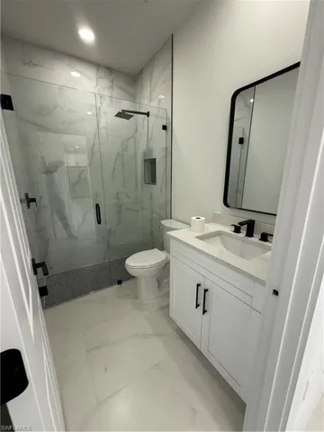 Full bath featuring vanity, recessed lighting, toilet, a marble finish shower, and marble finish floor