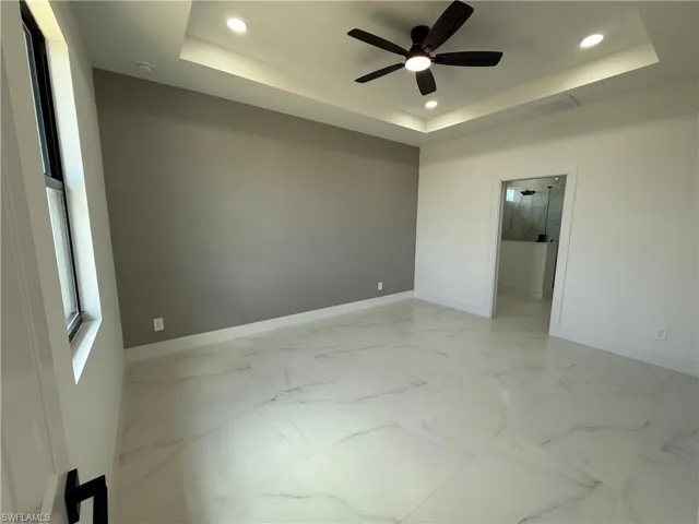 Spare room featuring baseboards, recessed lighting, visible vents, a tray ceiling, and marble finish floor