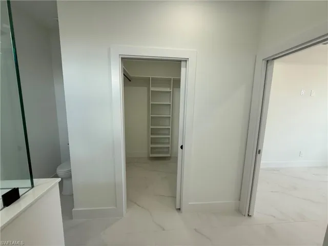 Bathroom with marble finish floor, baseboards, and toilet