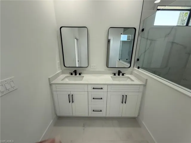 Bathroom featuring double vanity, marble finish floor, a sink, and a marble finish shower