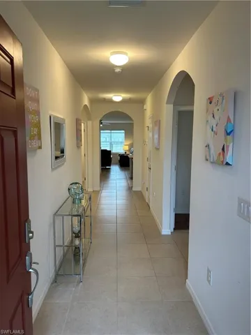 Corridor featuring light tile patterned flooring and arched walkways