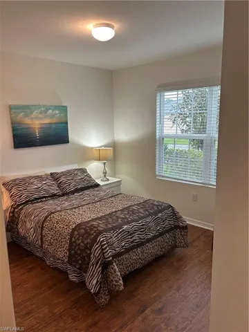 Bedroom with dark wood-style floors and baseboards