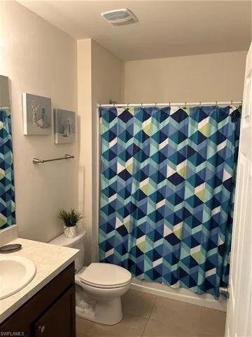 Bathroom featuring vanity, curtained shower, and light tile patterned flooring