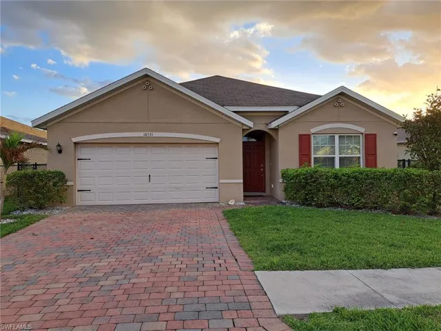 Single story home featuring stucco siding, a yard, an attached garage, and decorative driveway