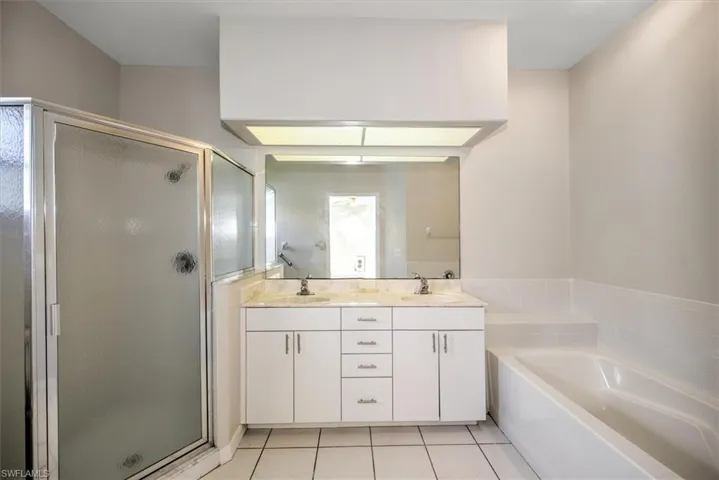Bathroom featuring tile patterned floors, vanity, and shower with separate bathtub
