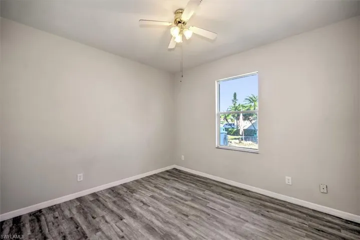 Empty room with ceiling fan and dark hardwood / wood-style floors