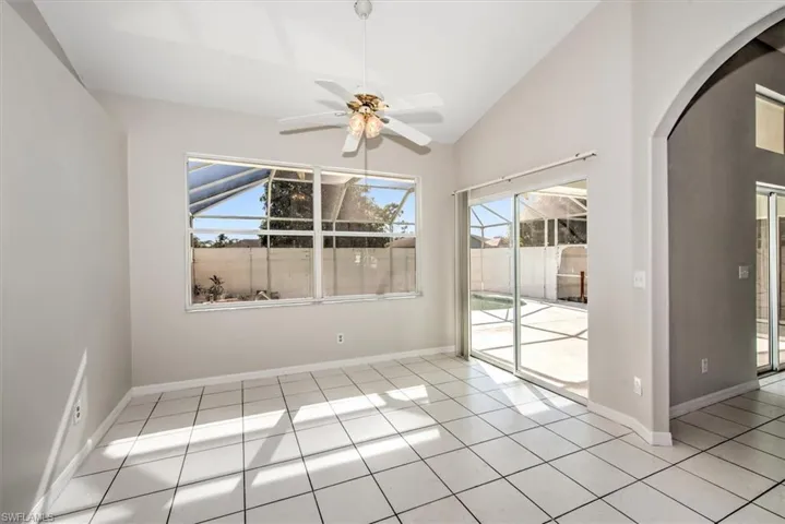 Tiled empty room with high vaulted ceiling, ceiling fan, and a wealth of natural light