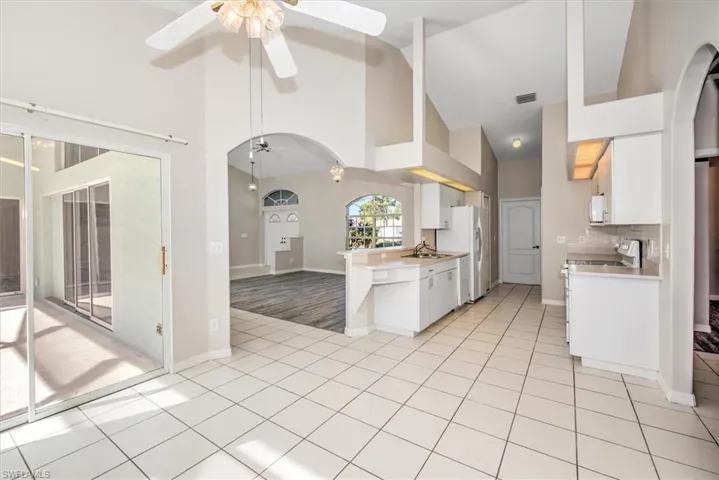Kitchen with white appliances, high vaulted ceiling, white cabinetry, and sink