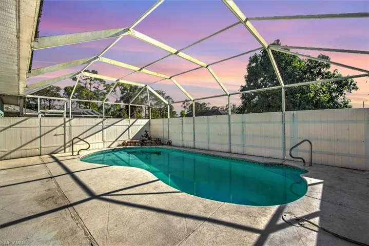 Pool at dusk featuring a patio and glass enclosure