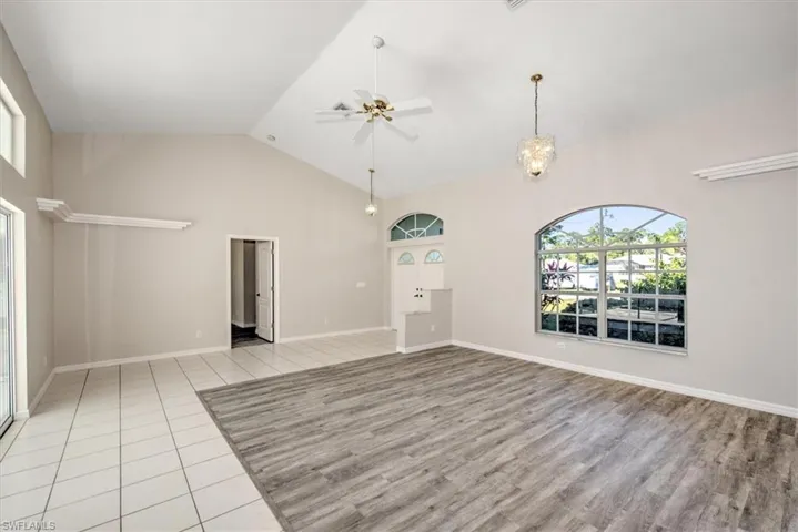 Unfurnished living room featuring ceiling fan, light hardwood / wood-style floors, and lofted ceiling