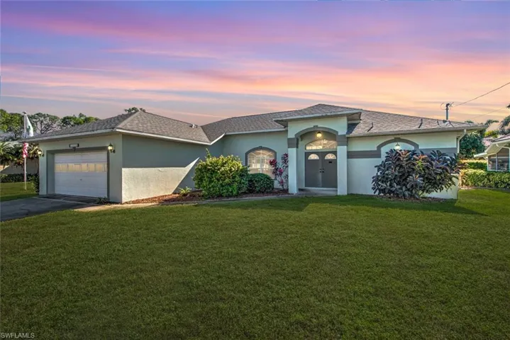 View of front facade featuring a yard and a garage
