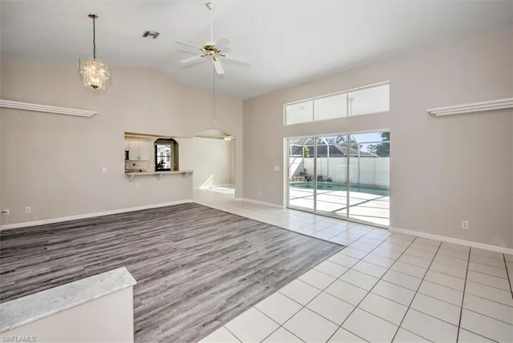 Unfurnished living room with ceiling fan, high vaulted ceiling, and light tile patterned floors
