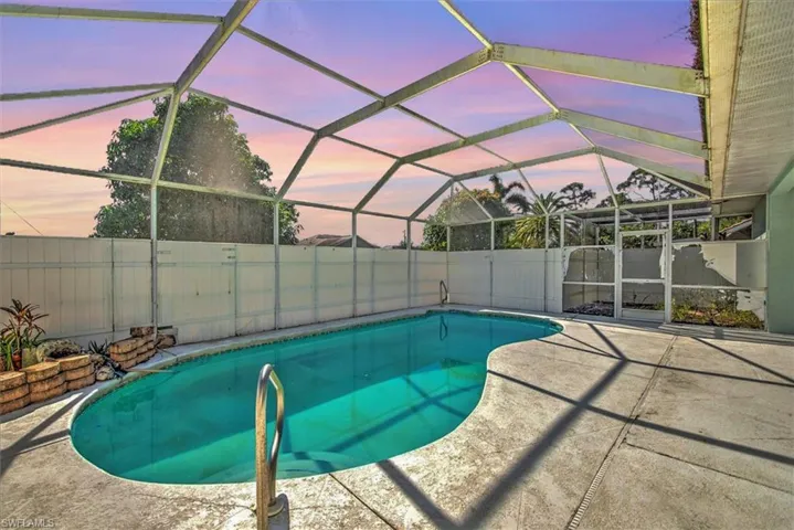 Pool at dusk featuring a lanai and a patio area