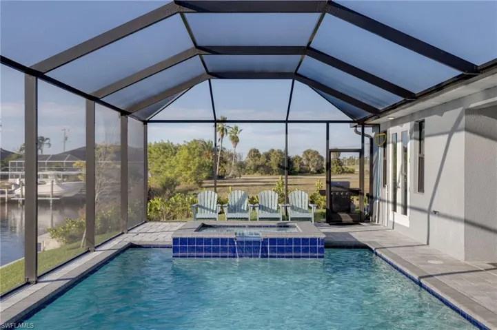View of pool featuring a sunroom, a lanai, a pool with connected hot tub, and a patio