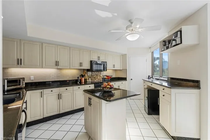 Kitchen featuring ceiling fan, sink, tasteful backsplash, cream cabinetry, and a kitchen island