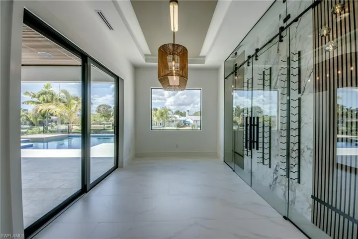 Wine room featuring a tray ceiling and light marble finish floors