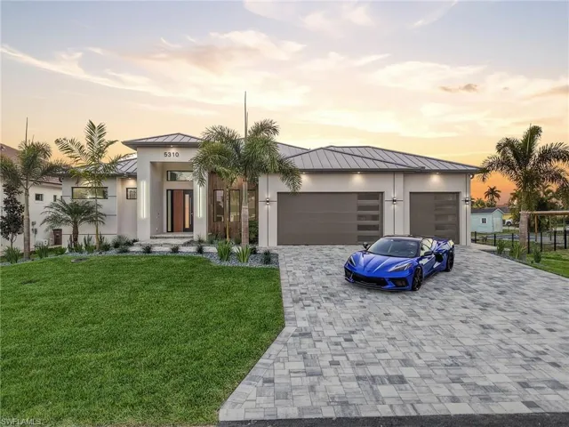 View of front facade featuring a standing seam roof, a front yard, decorative driveway, and an attached garage