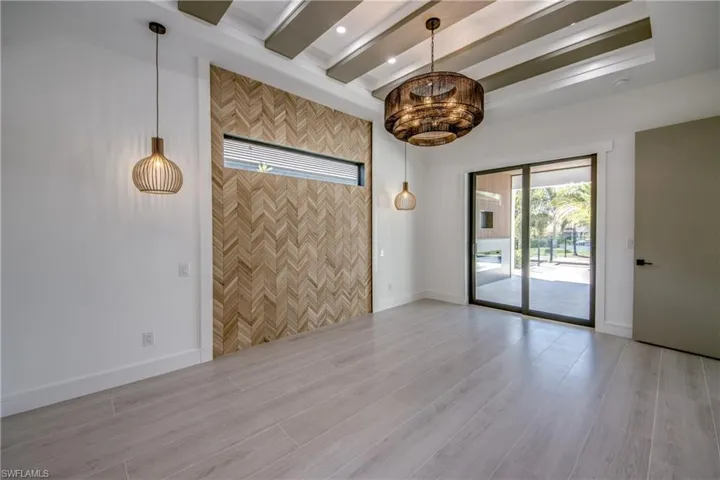 Empty room with light wood-style floors, beamed ceiling, and recessed lighting