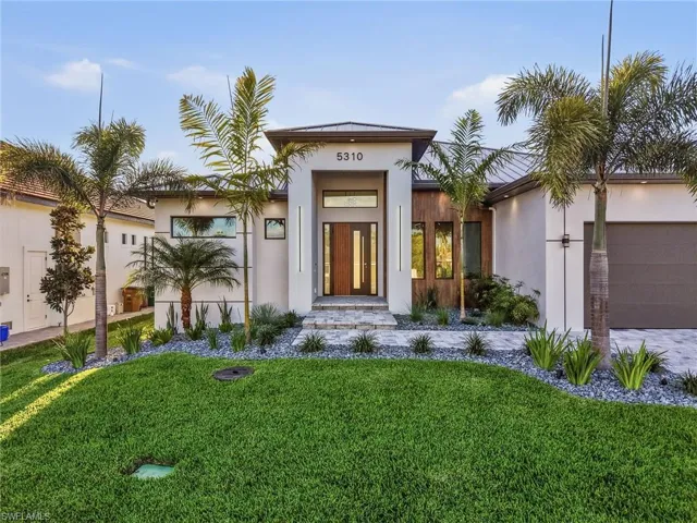 View of front of home with an attached garage, a front yard, and stucco siding