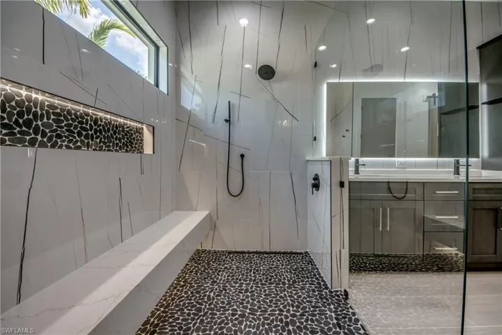 Bathroom featuring vanity and a marble finish shower
