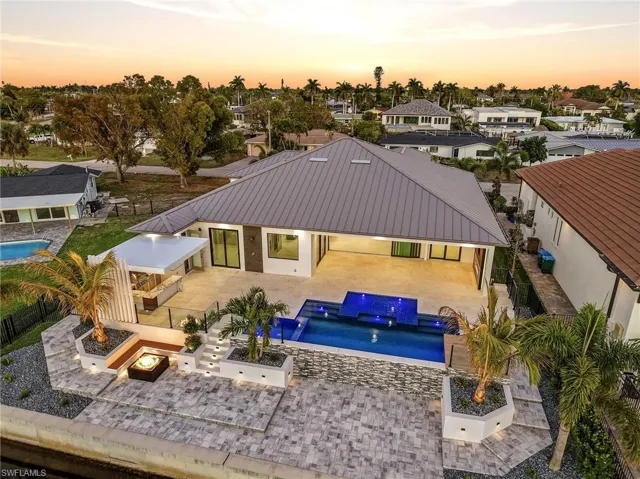 Back of house at dusk featuring a fenced backyard, an outdoor pool, a patio, and an outdoor fire pit