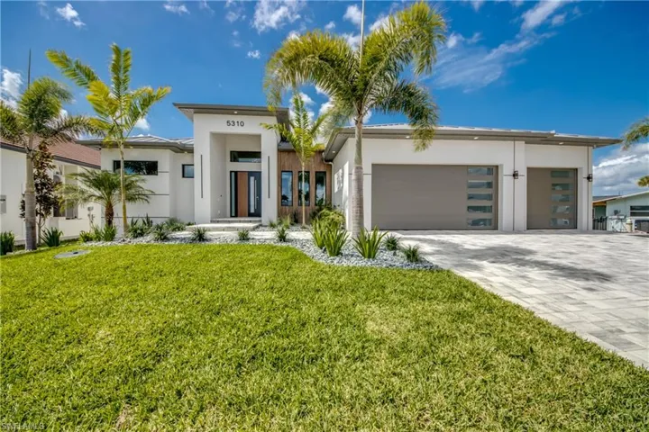 Contemporary house featuring decorative driveway, a garage, stucco siding, and a front yard