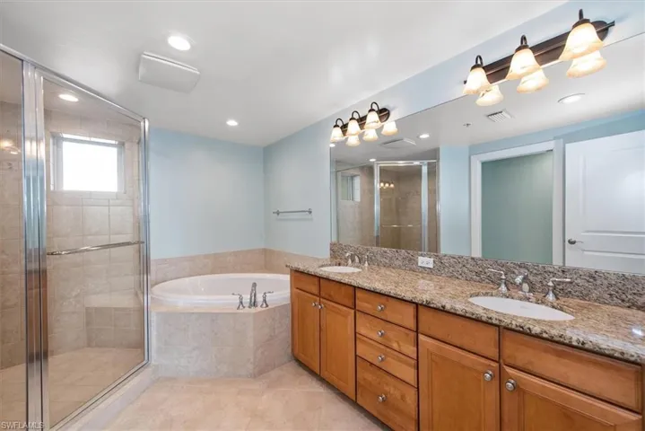 Full bathroom featuring a shower stall, double vanity, a garden tub, light tile patterned floors, and recessed lighting