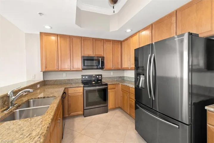 Kitchen featuring appliances with stainless steel finishes, light stone countertops, light tile patterned floors, and recessed lighting