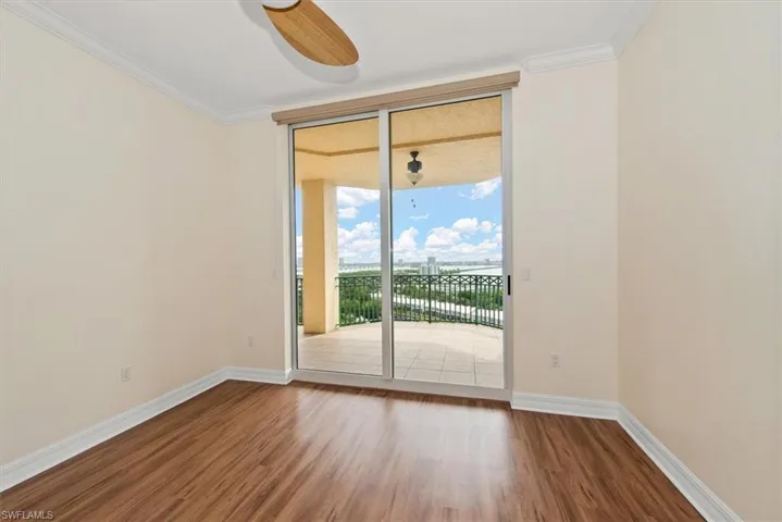 Empty room featuring crown molding, wood finished floors, and expansive windows