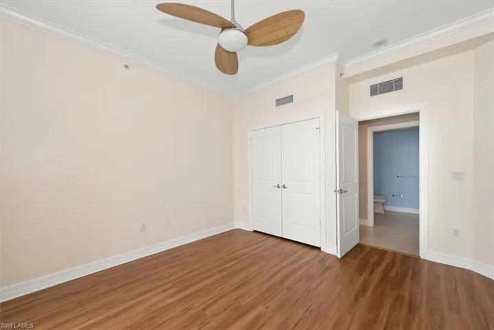 Unfurnished bedroom featuring ornamental molding, wood finished floors, a closet, and ceiling fan