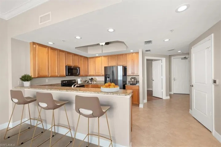 Kitchen featuring a breakfast bar, a peninsula, light stone counters, stainless steel appliances, and recessed lighting