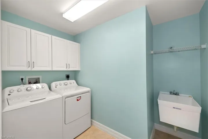 Washroom featuring washer and dryer, light tile patterned floors, and cabinet space