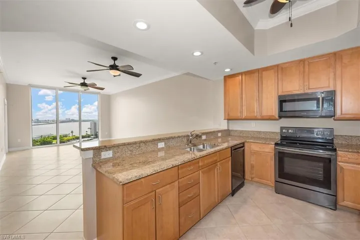 Kitchen with a ceiling fan, ornamental molding, stainless steel range with electric cooktop, a peninsula, and light stone countertops