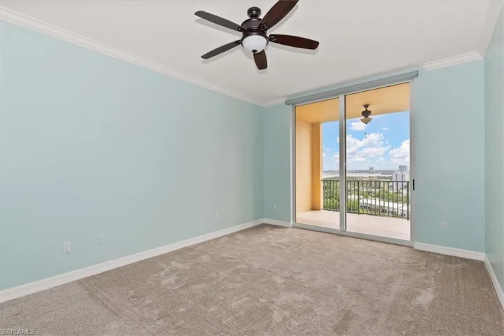 Carpeted spare room featuring crown molding, expansive windows, and ceiling fan