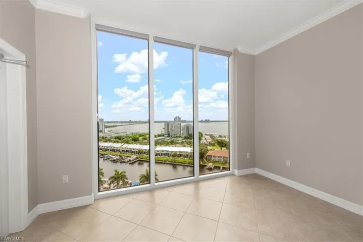 Unfurnished room featuring a wall of windows, ornamental molding, a city view, a water view, and light tile patterned floors