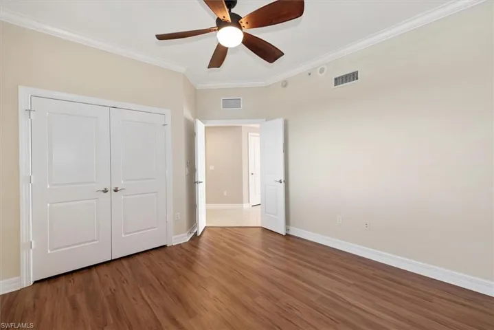 3rd bedroom featuring ornamental molding, wood finished floors, ceiling fan, and a closet