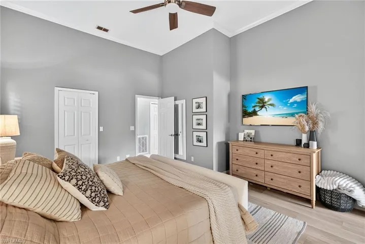 Bedroom featuring wood finished floors, a closet, ornamental molding, ceiling fan, and a high ceiling