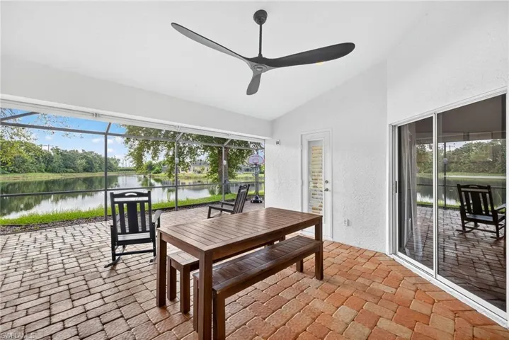 Sunroom / solarium featuring a patio area, lofted ceiling, a water view, and a ceiling fan