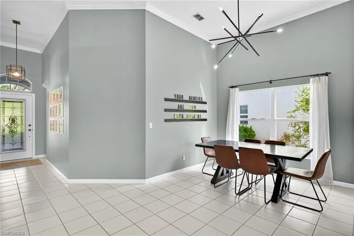 Tiled dining area with a high ceiling, a chandelier, and crown molding