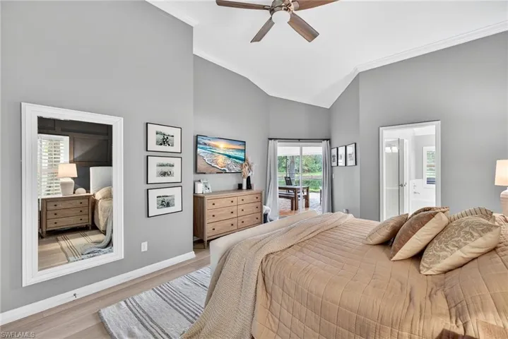 Bedroom with crown molding, wood finished floors, ceiling fan, high vaulted ceiling, and ensuite bathroom