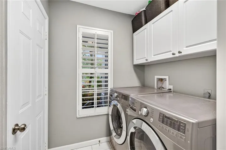 Laundry area with independent washer and dryer, cabinet space, and tile patterned floors