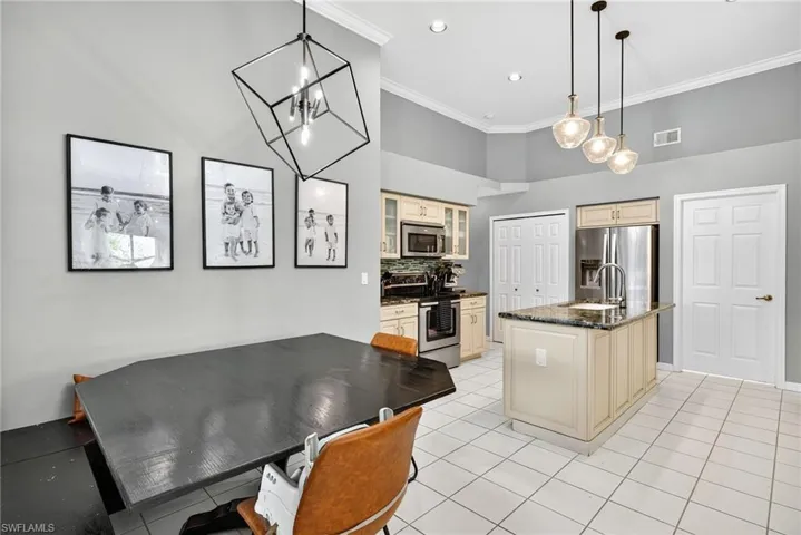 Kitchen featuring glass insert cabinets, appliances with stainless steel finishes, pendant lighting, tasteful backsplash, and crown molding