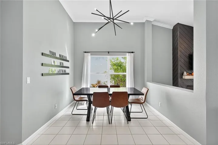 Dining area with ornamental molding, light tile patterned floors, a towering ceiling, and a chandelier