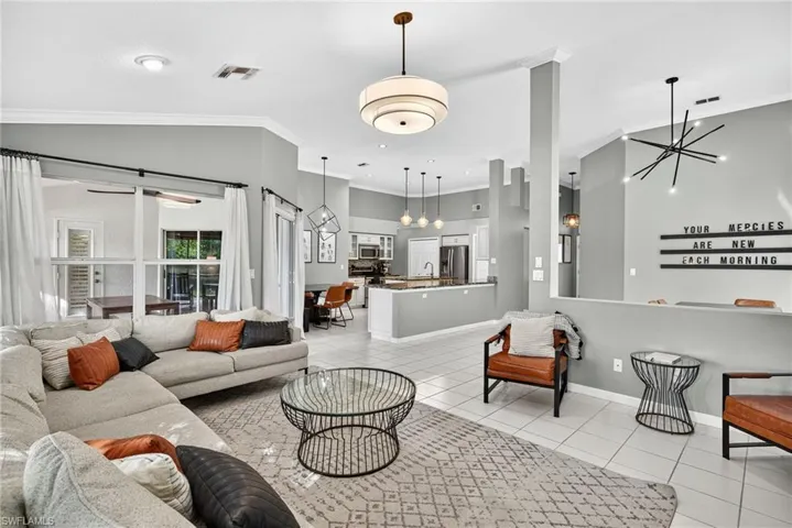 Living area featuring crown molding, light tile patterned flooring, and a chandelier