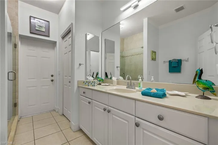 Bathroom with tile patterned floors, vanity, ornamental molding, and walk in shower