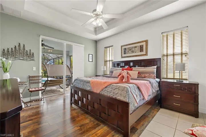 Bedroom with a raised ceiling, ceiling fan, and crown molding