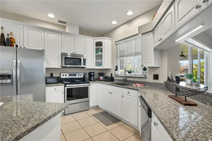 Kitchen featuring white cabinetry, sink, appliances with stainless steel finishes, and dark stone counters