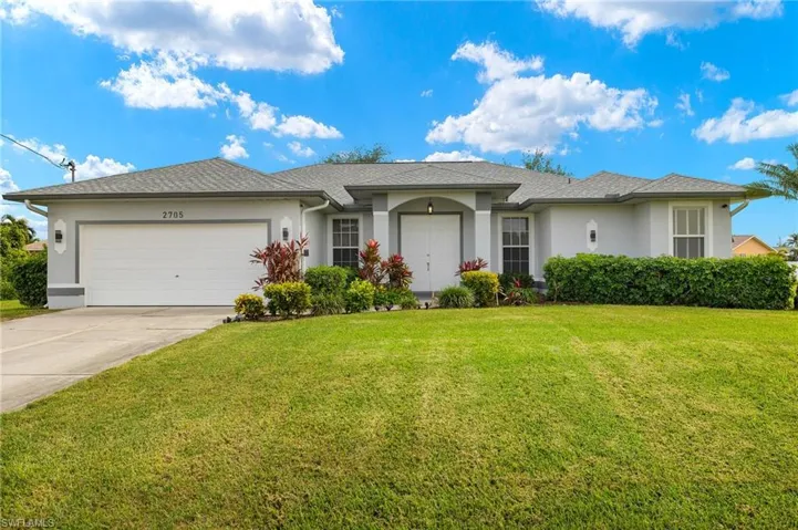 Single story home with a garage and a front lawn
