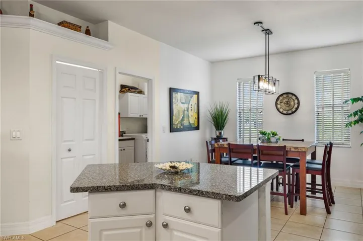 Kitchen with a center island, light tile patterned floors, an inviting chandelier, decorative light fixtures, and white cabinets